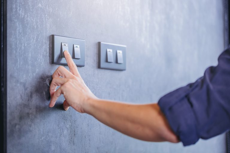 Close up of finger turn off on light switch at the wall. Energy